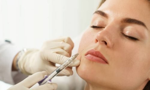 Female client during facial filler injections in aesthetic medical clinic